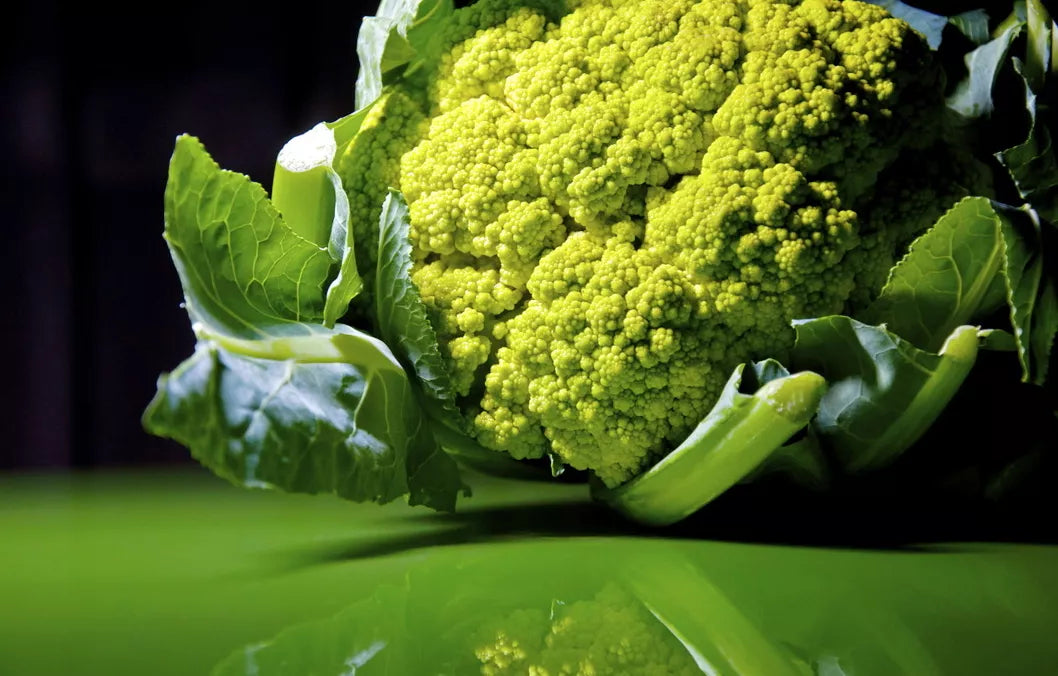 Brassica oleracea var. botrytis fresh green cauliflower head with leafy greens