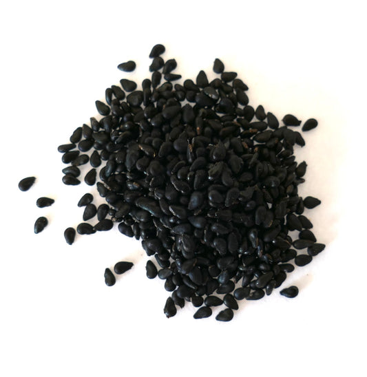 Diversi semi neri di Selenicereus grandiflorus su una superficie bianca