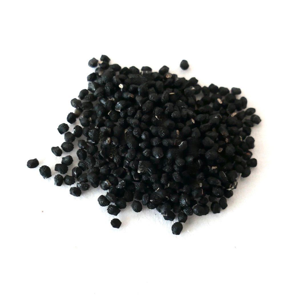 About one hundred small black seeds of Melocactus matanzanus on a white surface